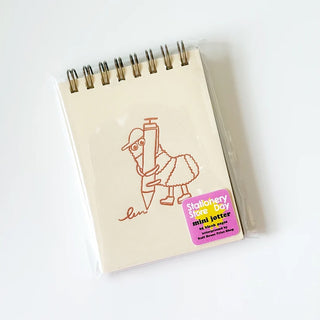A spiral-bound mini notebook featuring a cream-colored cover with an illustration of a bug holding a pencil and a label that reads 'Stationery Store Day mini jotter'.