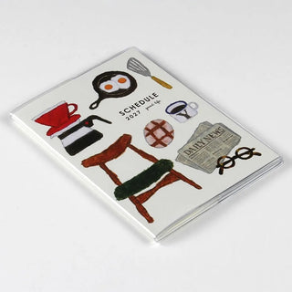 2027 A6 monthly planner cover with illustrated items on a clear sleeve