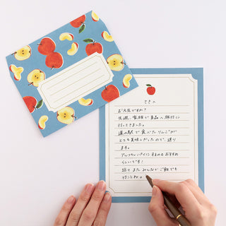 Letter set featuring apple designs and person writing on page