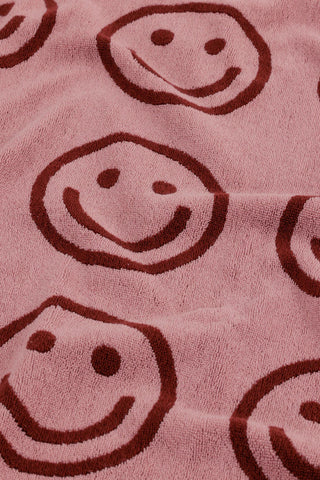 Blush bath towel close-up with smiling face pattern in dark ink