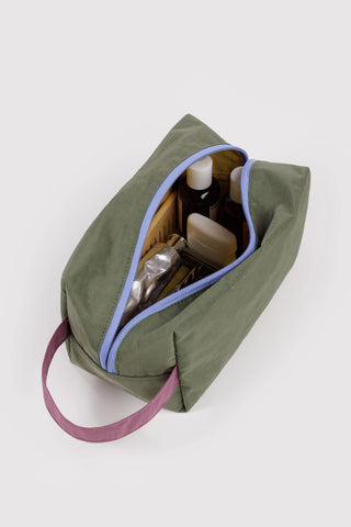 BAGGU dopp kit open, olive green with blue zipper trim, showing toiletries inside