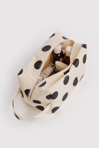 Cream dopp kit with black polka dots, open zipper top and visible interior compartments