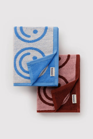 Set of 2 folded hand towels with smiling faces, blue and blush, BAGGU labels