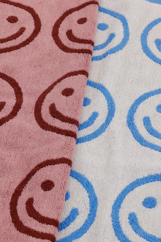 Close-up of hand towel pattern: smiling faces on blush and sky blue towels