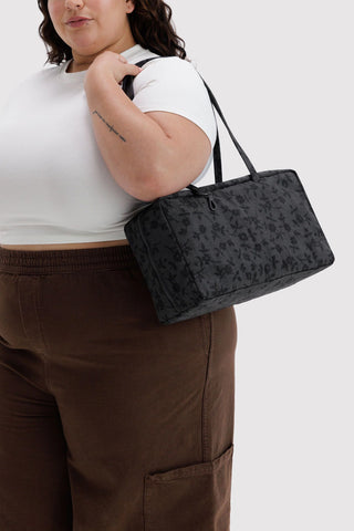 Medium nylon bowler bag on shoulder, charcoal floral print with top handles and zip.