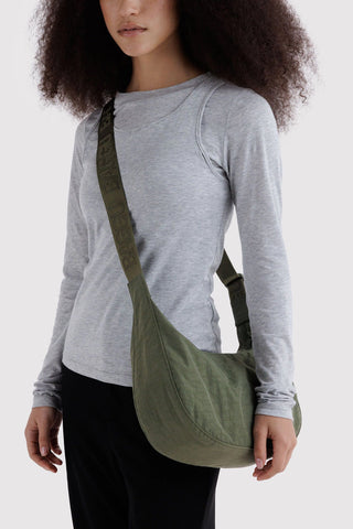 Olive crescent crossbody bag worn over shoulder with web strap and zipper pocket