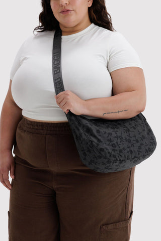 Charcoal floral crescent crossbody bag with logo web strap and front zipper opening