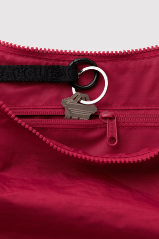 Crescent nylon bag closeup: cherry red zipper with keyring and front logo patch