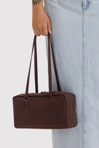 Coffee-brown nylon bowler bag held by top handles, front zipper visible