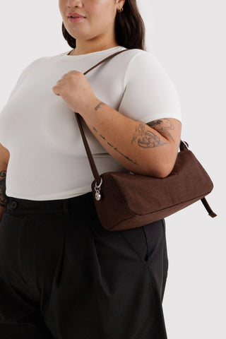 Person holding a brown purse over their shoulder against a white background