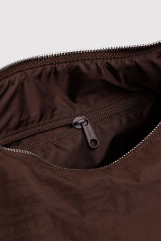 Close-up of a brown zipper on a bag with a light gray background