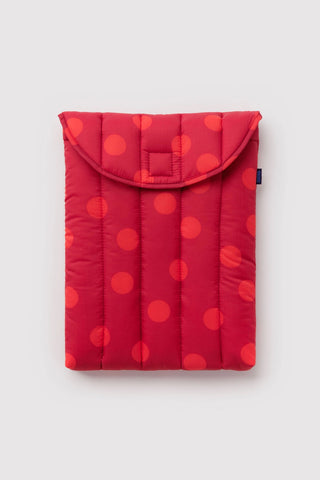Red quilted laptop sleeve with flap, rounded top, and orange polka-dot pattern.