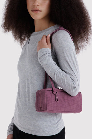 Plum nylon bowler bag worn on shoulder with short top handles