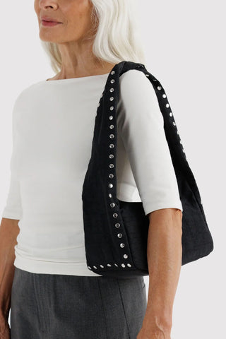 Studded black nylon hobo bag with carry handles, worn over shoulder