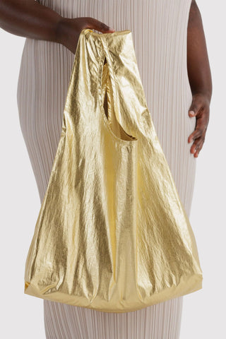 Gold metallic tote bag carried by one wide handle, gathered top