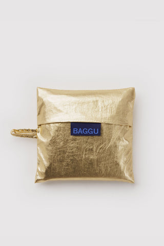 Folded gold metallic tote pouch with BAGGU label and gold clasp handle