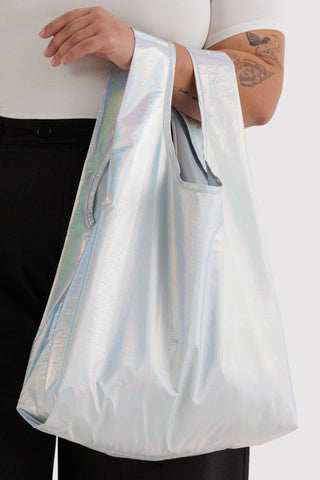 Person holding a reflective silver bag with a white shirt and black pants.