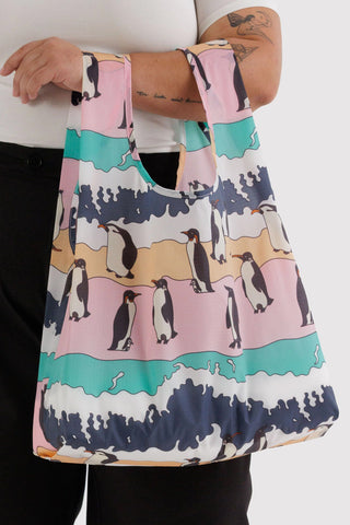 Person holding a colorful bag with penguin design