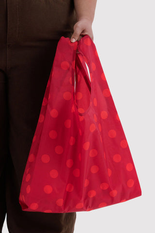 Red polka-dot reusable tote bag held by hand with open top