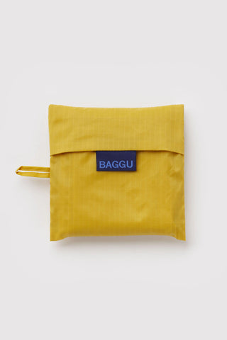 Folded sunflower-yellow BAGGU tote bag with blue logo patch and wrist strap