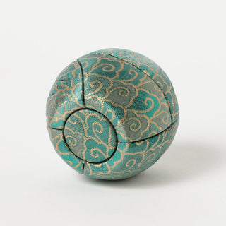 Back of green fabric daruma with gold patterns on a white background