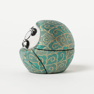 green decorative daruma with gold patterns on a white background