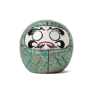 Decorative green daruma with face on a white background