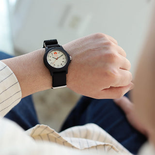 Person wearing a black wristwatch with a white face on a blurred background