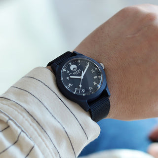 Person wearing a navy wristwatch with a blurred background