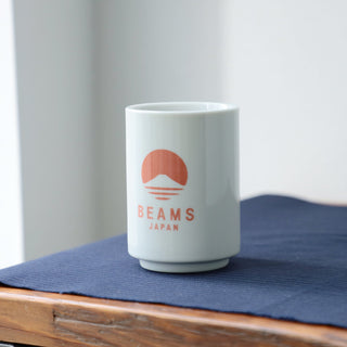 White mug with red logo and 'Beams Japan' text on a blue mat