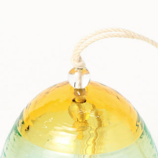 Glass wind chime with a yellow top and string on a white background