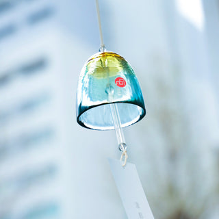 Colorful glass bell shaped wind chime with a blurred natural background