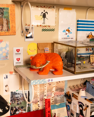 Orange bear coin bank on a shelf with various items and decorations in the background