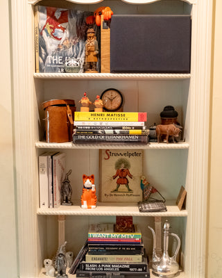 Bookshelf with various items including books, figurines, and a clock.
