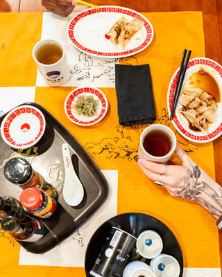 Top-down view of a dining table with food and drinks on an orange checkered tablecloth.