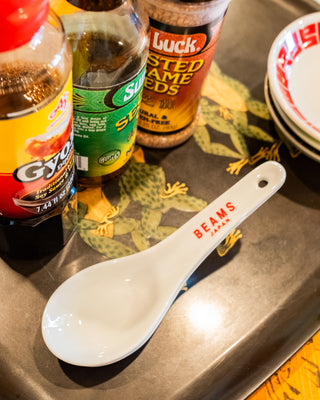 Spoon with 'Beans' branding on a tray with condiment bottles in the background