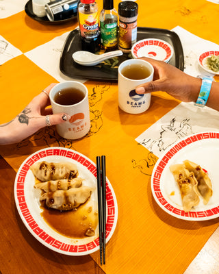 Two people enjoying dumplings with drinks at a table, featuring 'Beanm' branding.