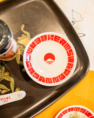 Round white small dish with red circular beams logo design on a tray