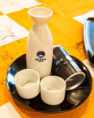 Sake set with cups inside of a dish on a orange tablecloth