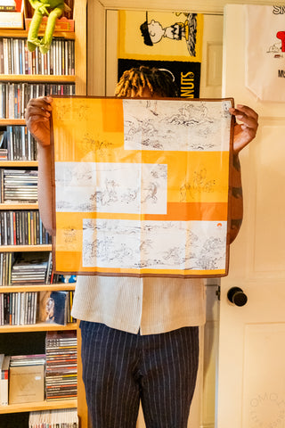 Person holding a large orange and white handkerchief in front of a bookshelf.