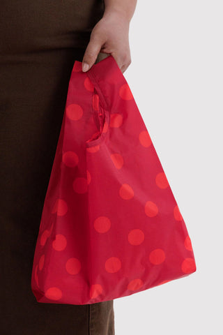 Red polka-dot tote bag with short carry strap, held by hand