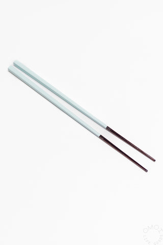 Two light blue bamboo chopsticks on a white background