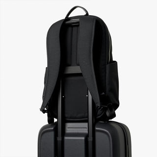 Black backpack on a black suitcase against a white background