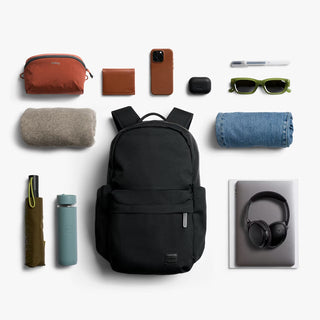 Black backpack surrounded by various items on a white background