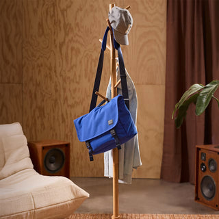Coat rack with a blue bag and gray cap in a living room setting