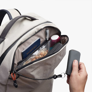 Backpack with items like a passport and snacks, held open by a hand holding keychain