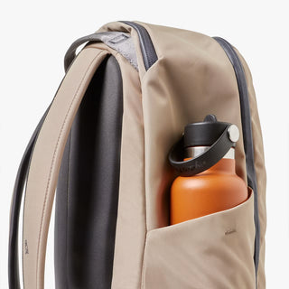 Beige backpack with a water bottle in a pocket on a white background