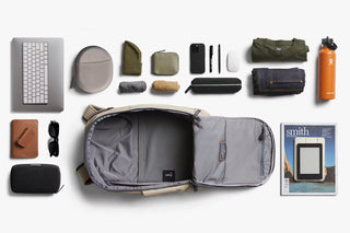 Collection of travel accessories including a backpack, keyboard, phone, and other items on a white background.