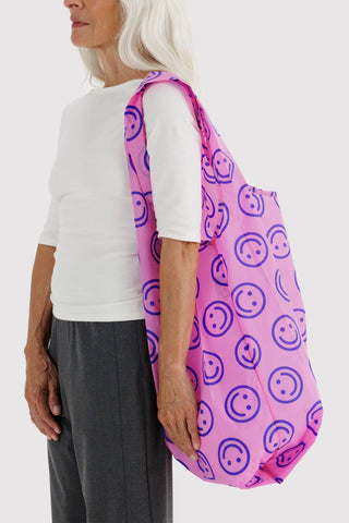 Pink smiley-pattern tote bag carried by hand on a shoulder strap