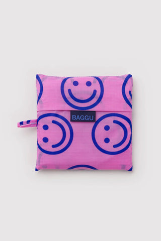Folded pink smiley-pattern storage pouch with BAGGU label and carrying strap